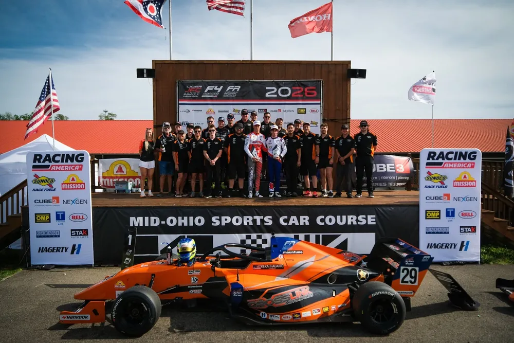 The Crosslink Motorsports team gathered behind an orange Formula 4 car at Mid-Ohio Sports Car Course
